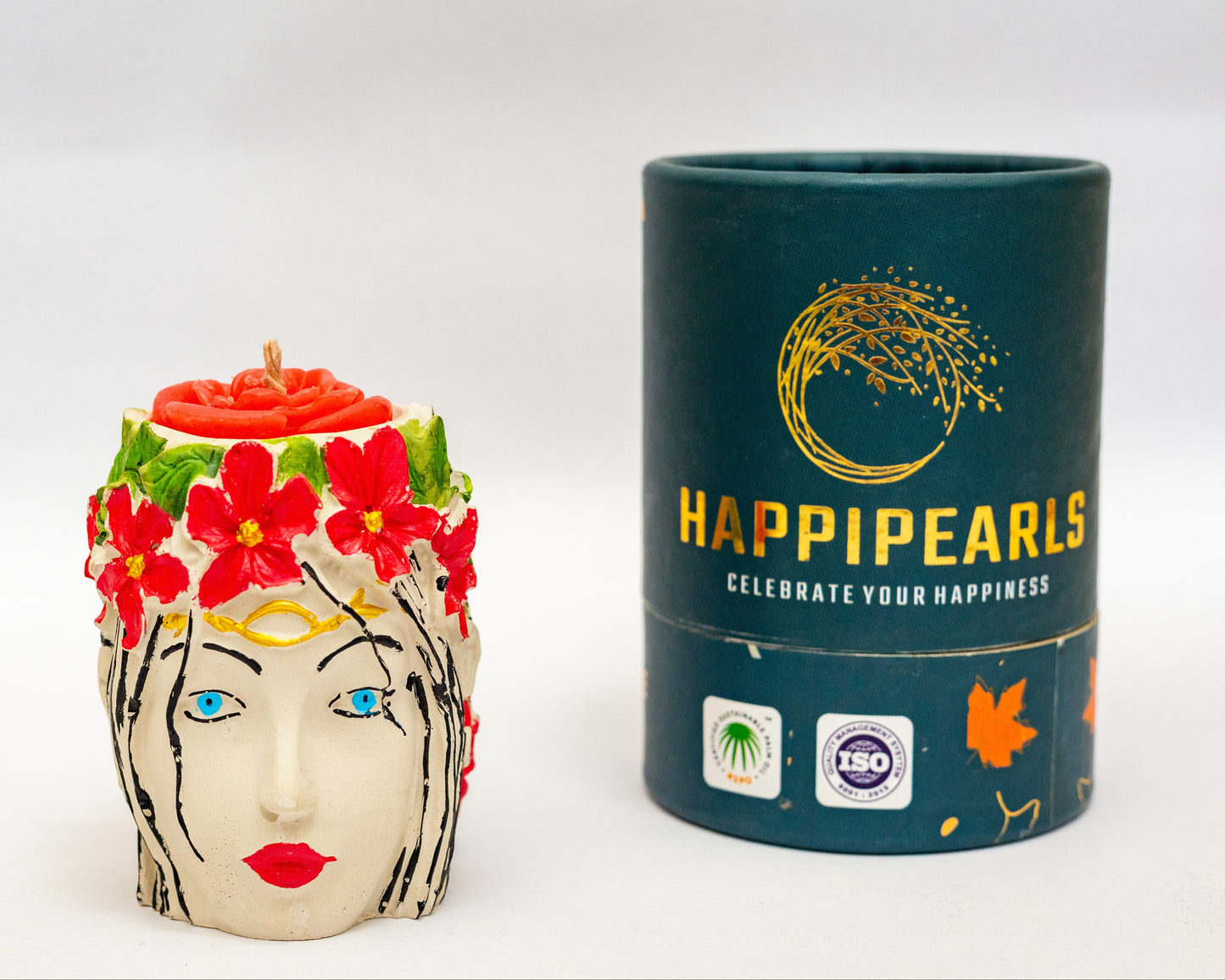 Decorative candle shaped like a face with flowers and a cylindrical container labeled 'Happipears' on a white background.